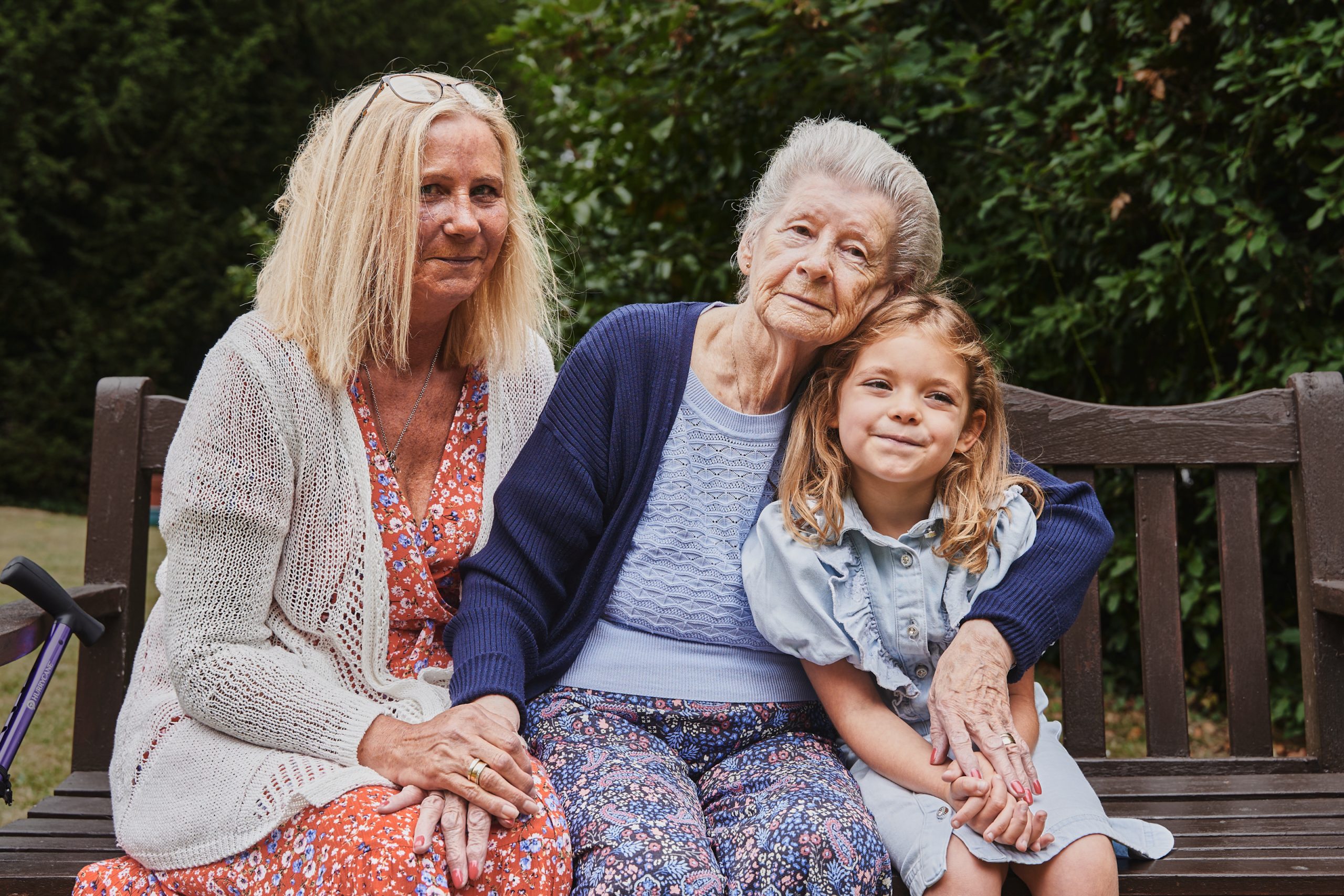 Two women and one child sitting on a bench, hugging and holding hands